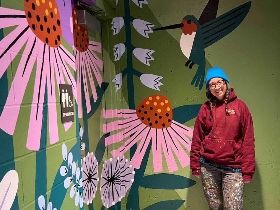 Artist Emily Balsley poses in front of her Comfort Station Mural