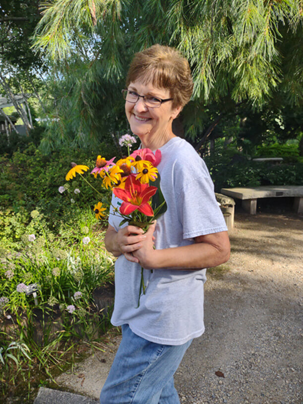An RBG volunteer poses while holding flowers