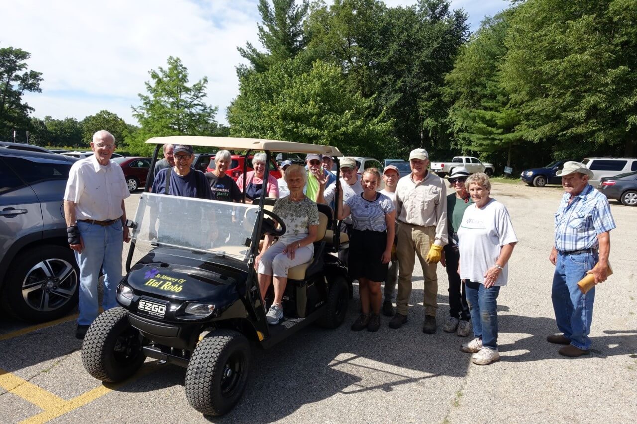 Emma Wallace and a group of RBG volunteers pose near a golf cart